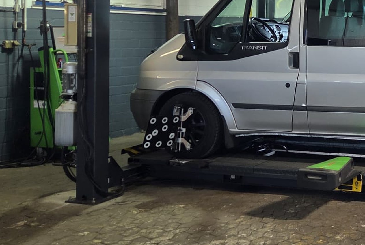Messkopf der Achsvermessung am Vorderrad eines Transporters auf der Bühne.