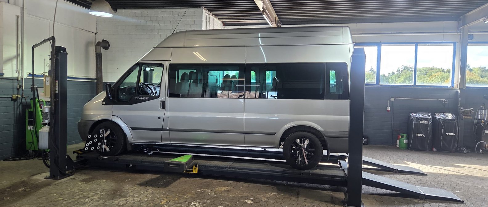 Ein Transporter steht zur Achsvermessung auf der Vier-Säulen-Bühne, an den Vorderrädern sitzen die Messköpfe.